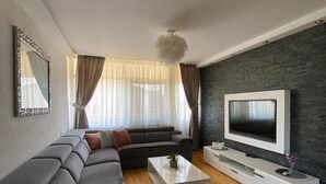 A modern living room with a sectional sofa, a flat-screen TV, and a minimalist coffee table. - Apartments Nada (Sucuraj)