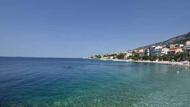 A coastal town with clear blue waters, a sandy beach, and buildings along the shore. - Apartment Green (Dugi Rat)