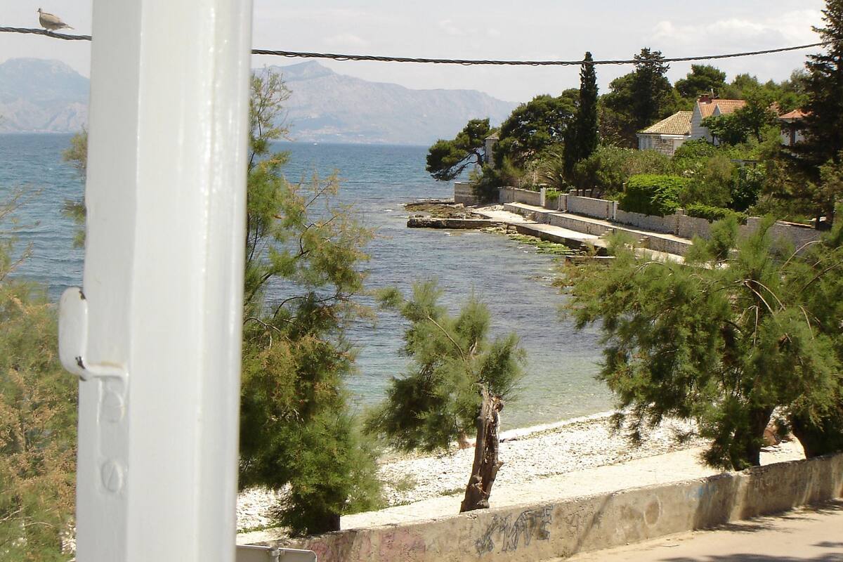 A coastal view with a clear sky, a body of water, and a stone pathway leading to a beach.