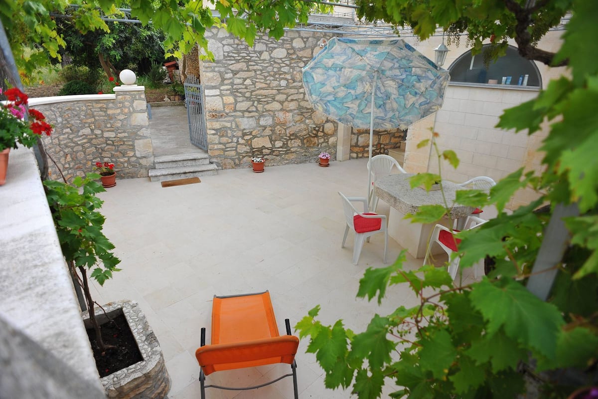 A patio area with stone walls, a table with chairs, and potted plants.