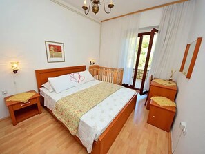 Une chambre à coucher avec un lit en bois, une table de chevet, une commode et une fenêtre avec des rideaux.