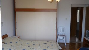 A bedroom with a bed, a wardrobe, a chair, and a television. - Apartment Eta (Hvar)