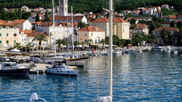 A marina with boats docked, surrounded by buildings with red-tiled roofs. - Apartments Marino (Supetar)