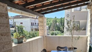 A covered outdoor patio with a table and chairs, a bench, and potted plants. - Apartments Marino (Supetar)