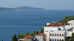 A coastal building with a view of the sea and distant hills. - Apartments and Room Dar (Hvar)