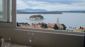 A table with a glass and a napkin, overlooking a lake with a distant island and buildings. - Apartments and Room Dar (Hvar)