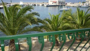 A marina with boats docked, palm trees, and a building in the background. - Apartment Smil (Sucuraj)