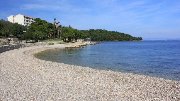 Una playa de guijarros con un edificio al fondo.