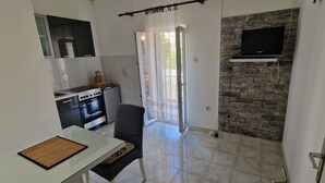 Una cocina compacta con estufa, horno y comedor con mesa y silla.