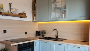 Een moderne keuken met lichtblauwe kastjes, een zwarte oven en een houten aanrecht.