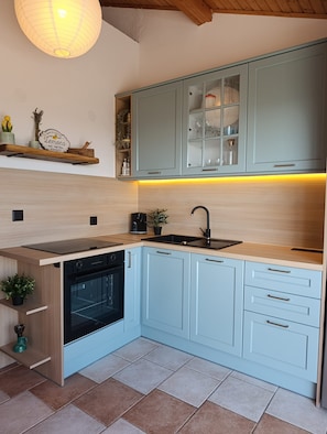A modern kitchen with light blue cabinets, a black oven, and a wooden countertop. - Apartments Josip (Jelsa)