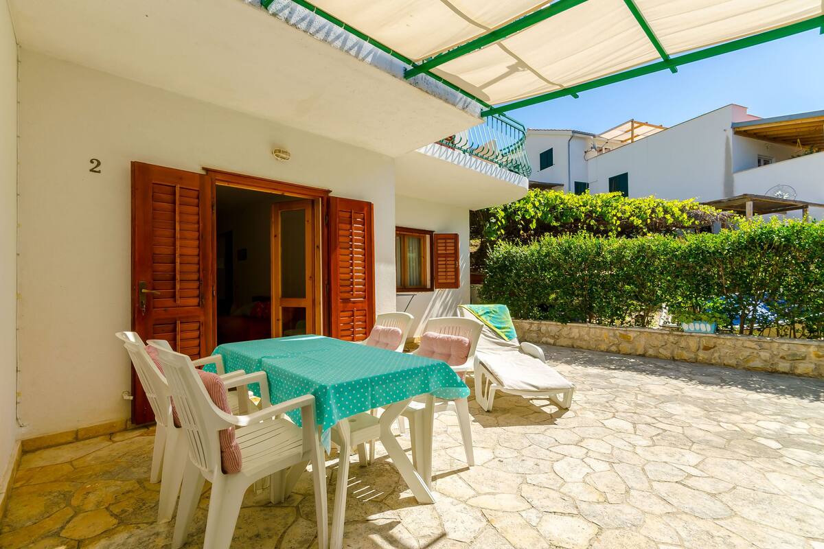 A patio with a table and chairs, a covered area, and a stone floor.
