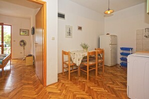 Kompakti keittiö, jossa on ruokapöytä, tuolit, jääkaappi ja pesukone.