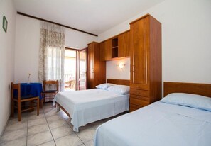 A room with two beds, a wooden wardrobe, a desk with a chair, and a window with curtains. - Apartments Juri (Sucuraj)