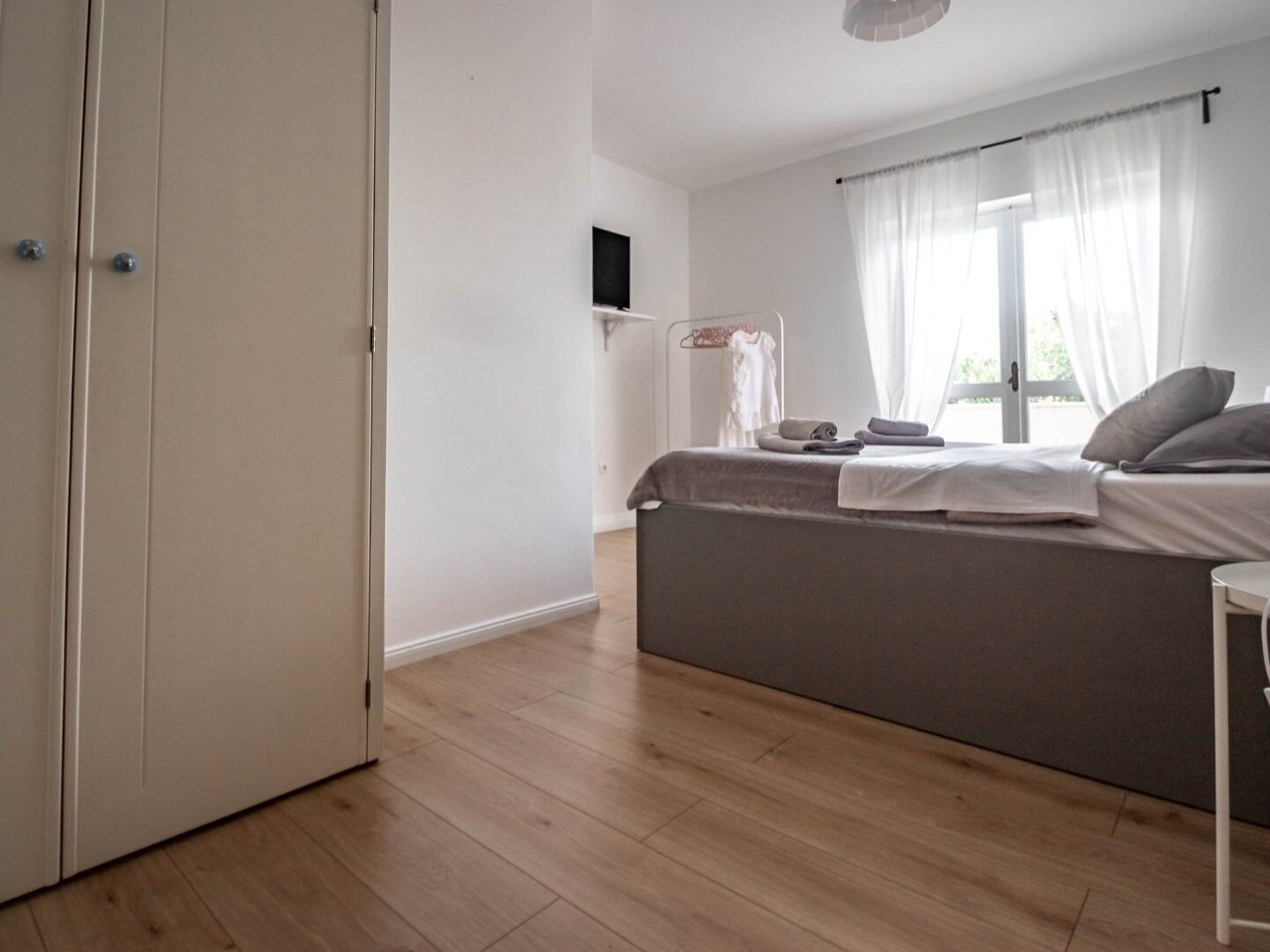 Una camera da letto con un letto, una TV a parete e una finestra con tende.