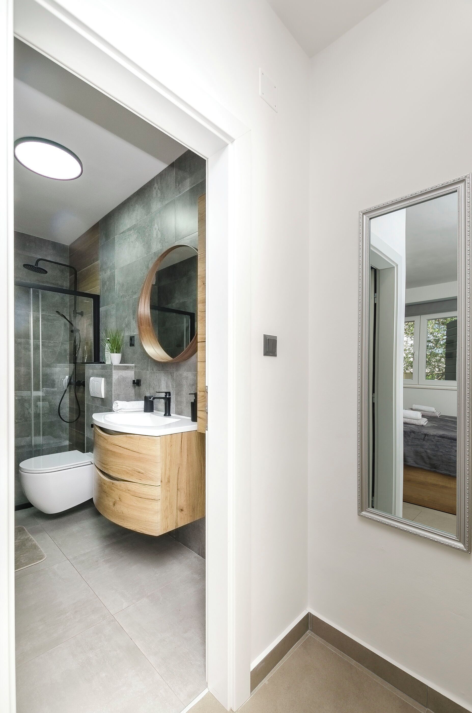 Une salle de bain moderne avec une douche à parois de verre, un meuble-lavabo en bois et un grand miroir.