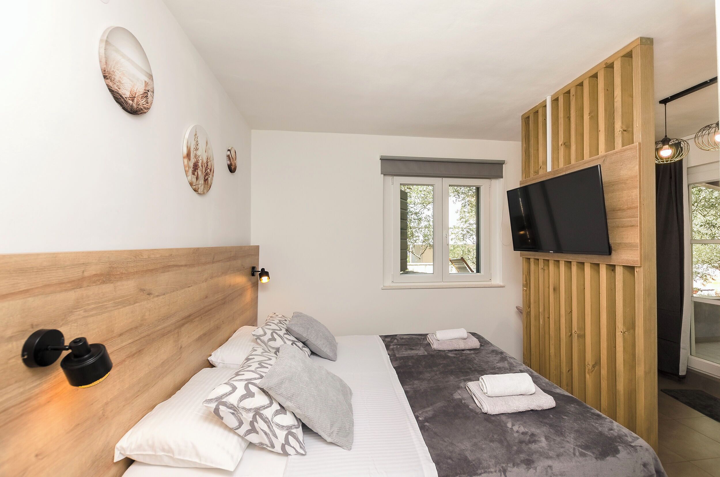 A bedroom with a bed, pillows, a TV, and a window.