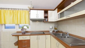 A compact kitchen with a window, a sink, and a coffee maker. - Apartments Vinko (Primosten)