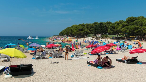 A beach with umbrellas, sun loungers, and people. - Apartments Vinko (Primosten)