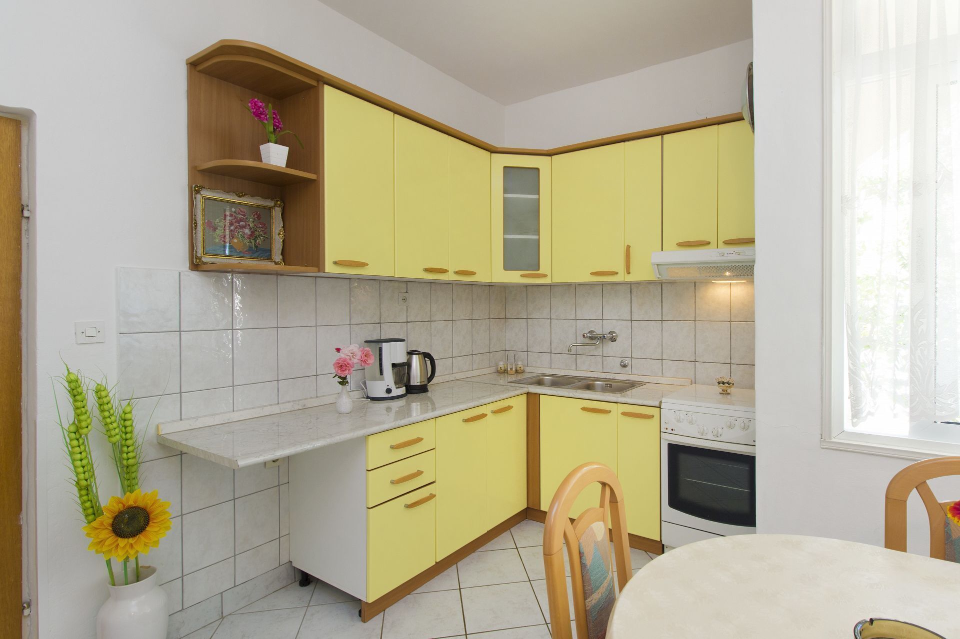 A kitchen with yellow cabinets, a white countertop, and a dining area with a table and chairs.