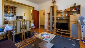Ein Wohnzimmer mit Essbereich, Fernseher und Ventilator.