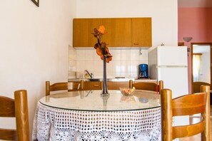 A round glass table with a crocheted tablecloth, surrounded by wooden chairs. A vase with dried flowers is placed on the table. - Apartment VV (Seget)