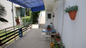 Eine überdachte Terrasse im Freien mit Tisch, Stühlen, Blumentöpfen und einem blauen Baldachin.