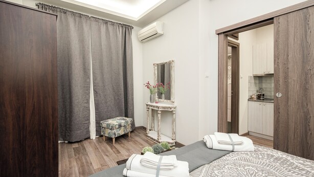 Une chambre à coucher avec un lit, une table de chevet, un miroir et un petit tabouret.