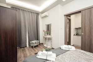 A bedroom with a bed, a bedside table, a mirror, and a small stool. - Socrates - Premium Athenian Apartment near Acropolis (Athina)