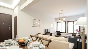 Un coin repas avec une table en bois dressée pour le repas, un canapé et un téléviseur en arrière-plan.