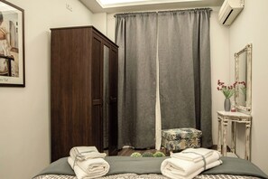 A bedroom with a bed, a wardrobe, a small table with a vase, and a mirror. - Socrates - Premium Athenian Apartment near Acropolis (Athina)