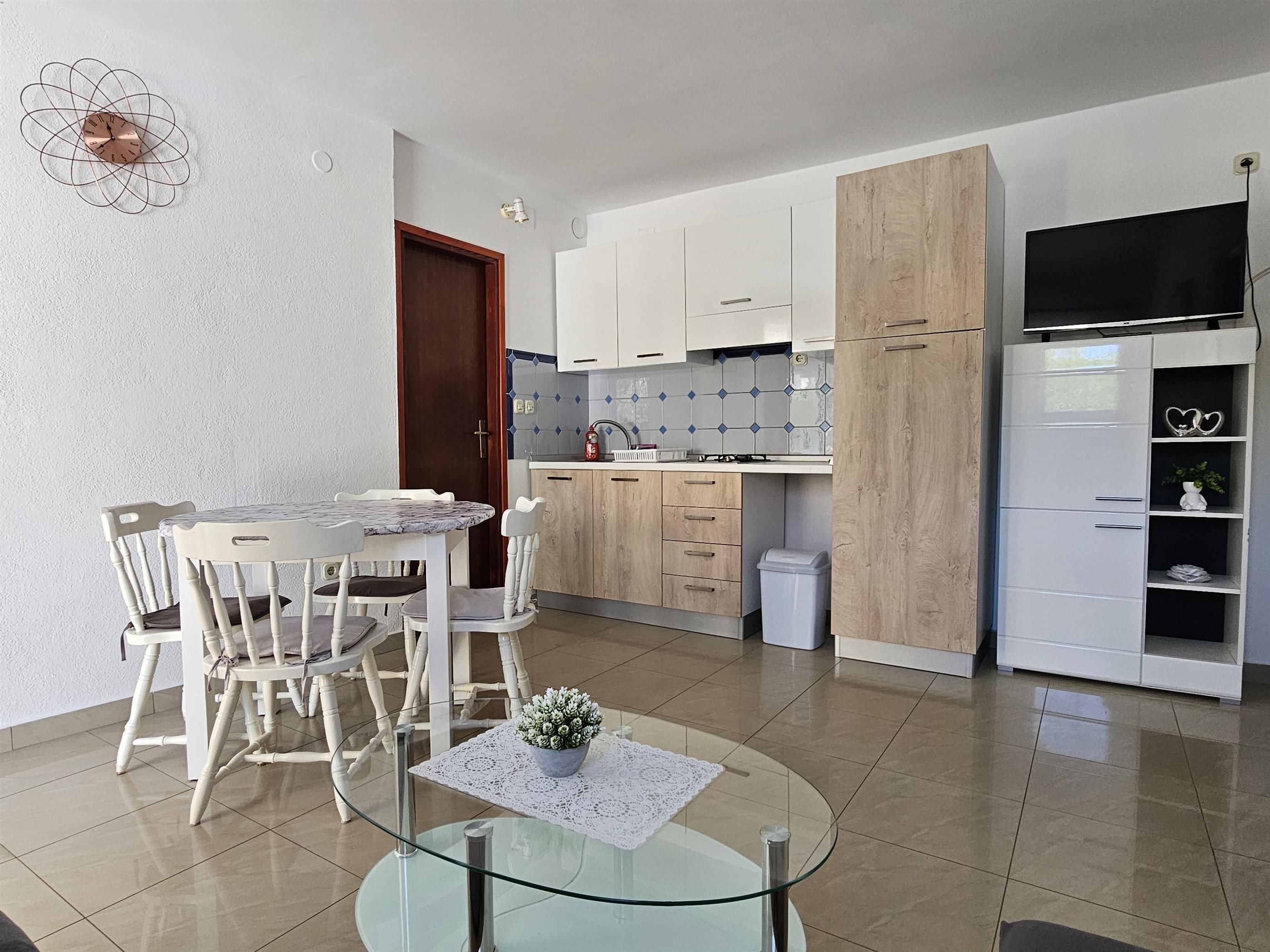 A modern kitchen with white cabinets, a built-in oven, and a white refrigerator.