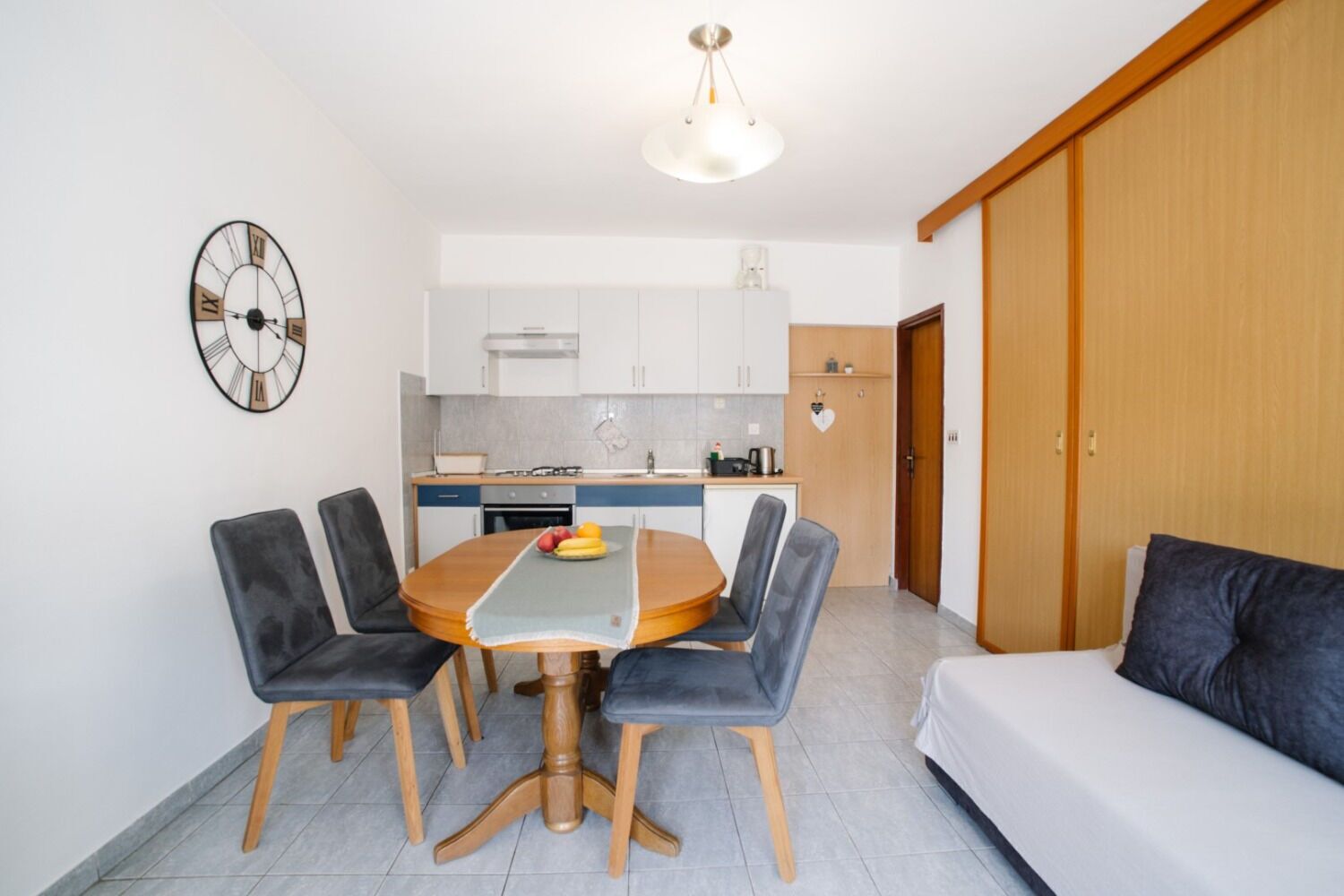 A compact living space with a dining area, kitchenette, and a sofa.