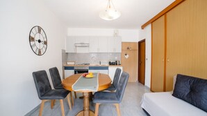 A compact living space with a dining area, kitchenette, and a sofa. - Apartments Petri (Tisno)