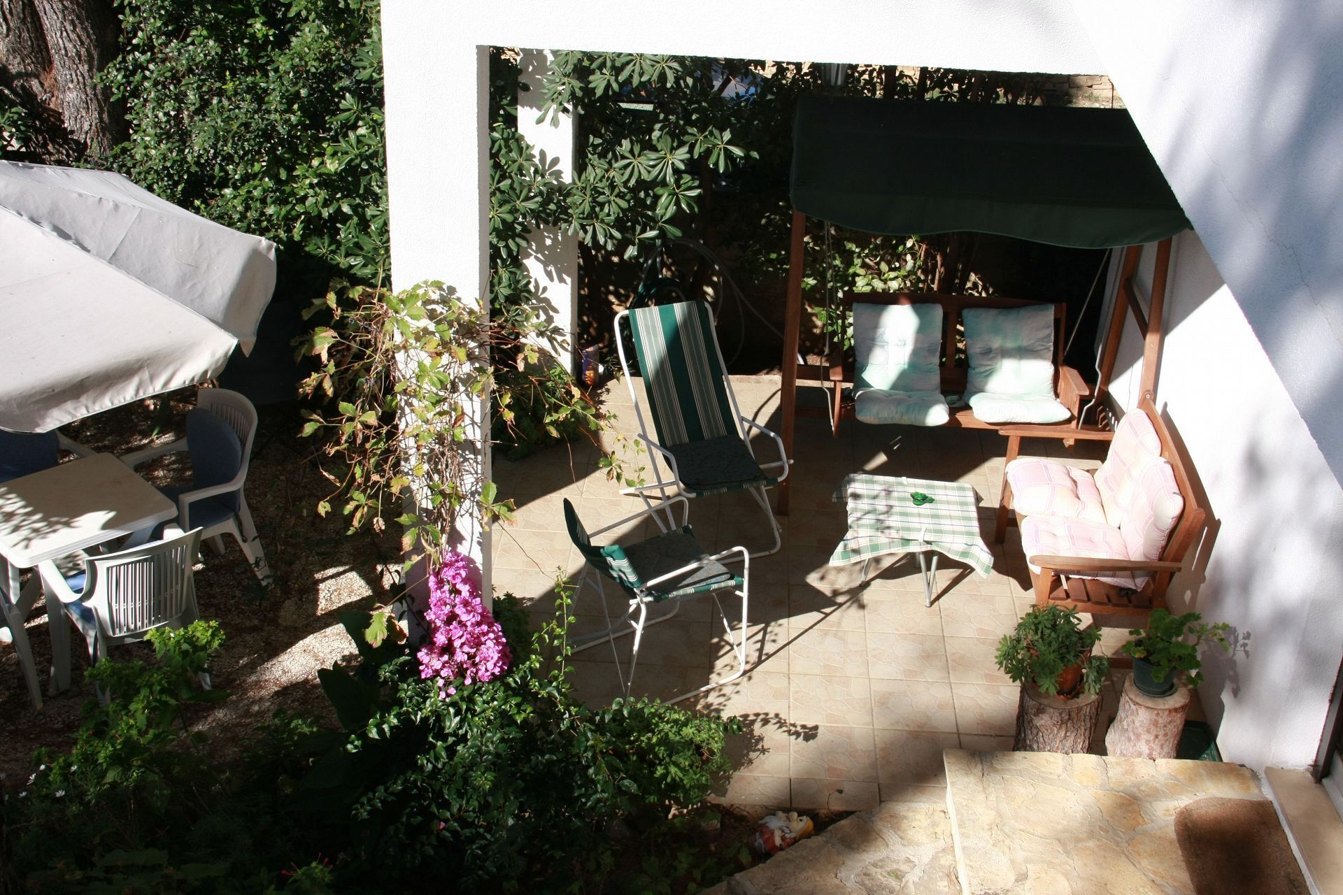 A patio area with a table and chairs, a covered seating area, and potted plants.