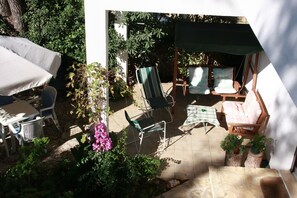 A patio area with a table and chairs, a covered seating area, and potted plants. - Apartments Dinka (Supetar)