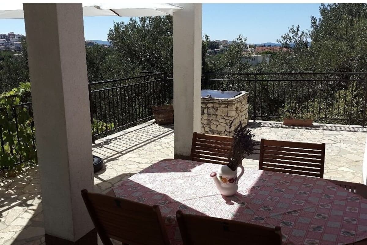 Un balcon avec une table, des chaises, un jardinière en pierre et une vue sur la ville.