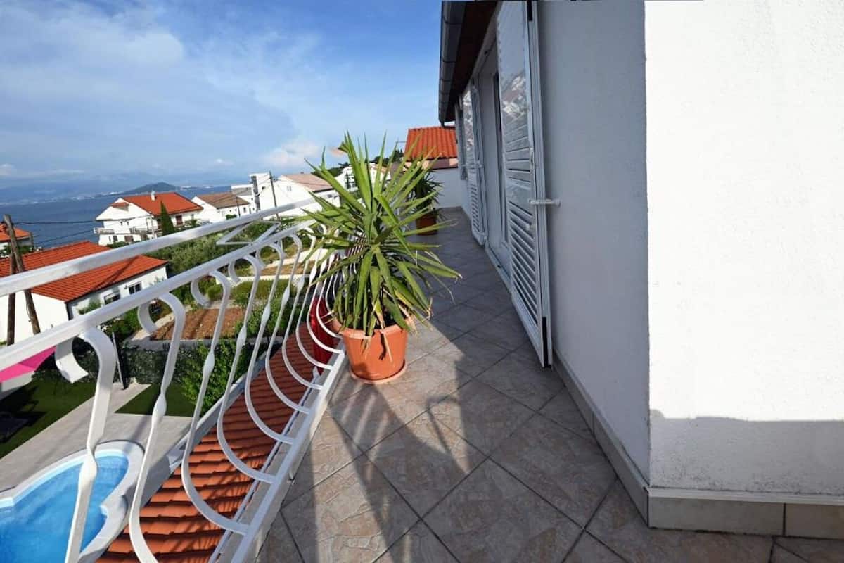 A balcony with a potted plant, a pool, and a view of the sea.