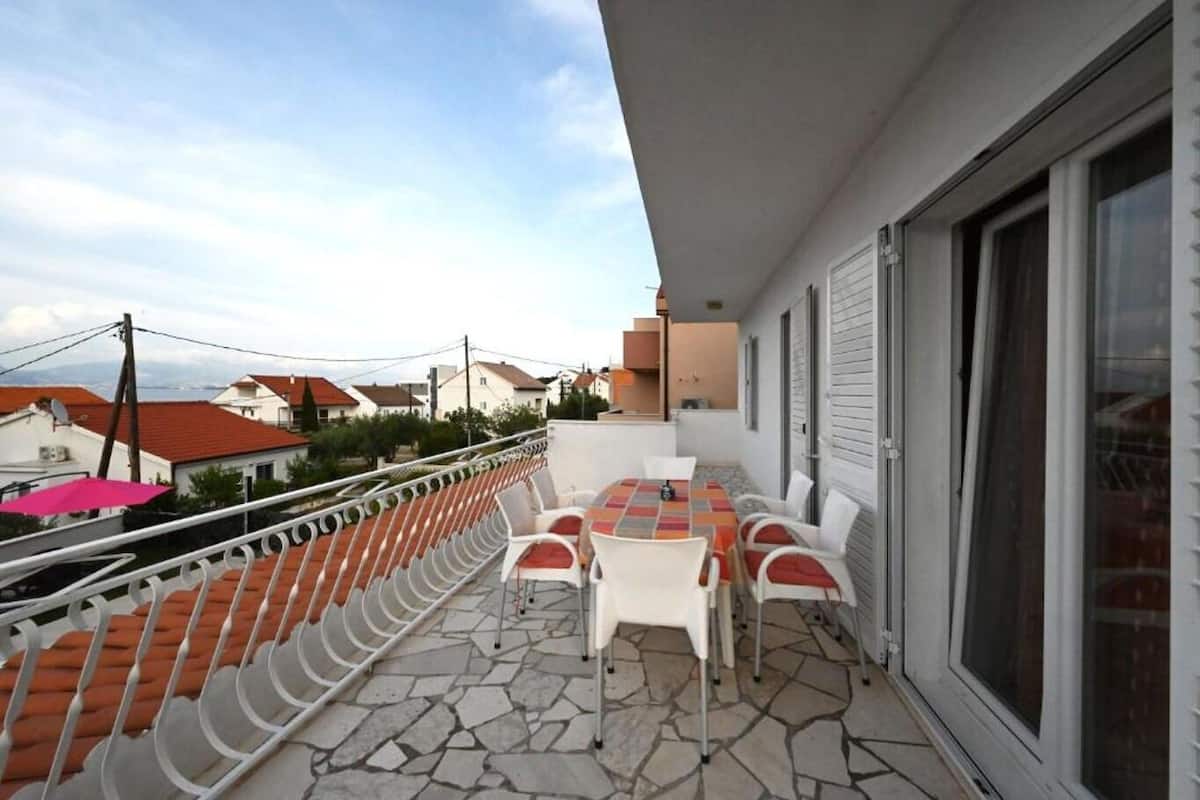 A balcony with a table and chairs, a railing, and a view of neighboring buildings.