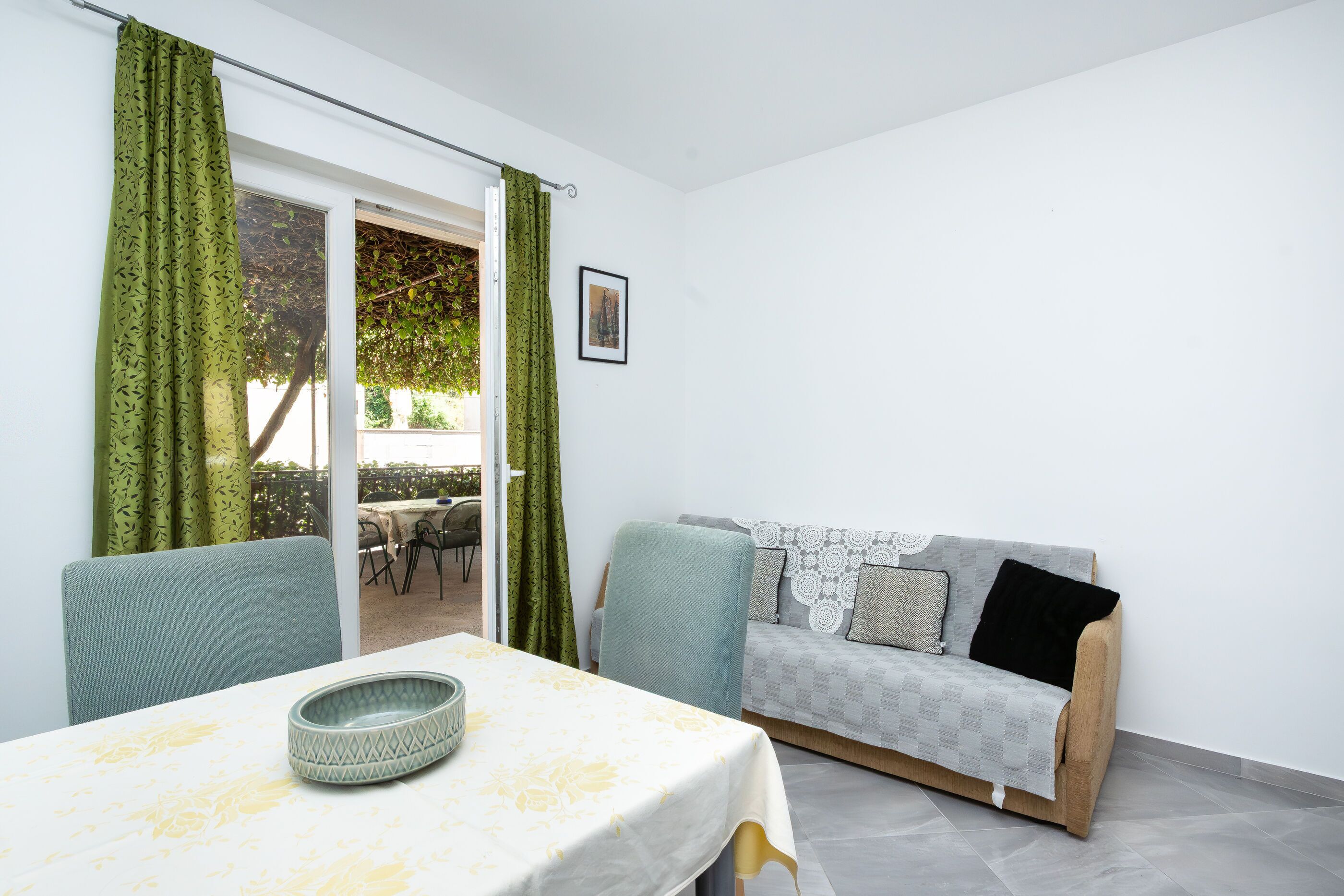 A room with a dining table, a sofa, and a view of the outdoors.