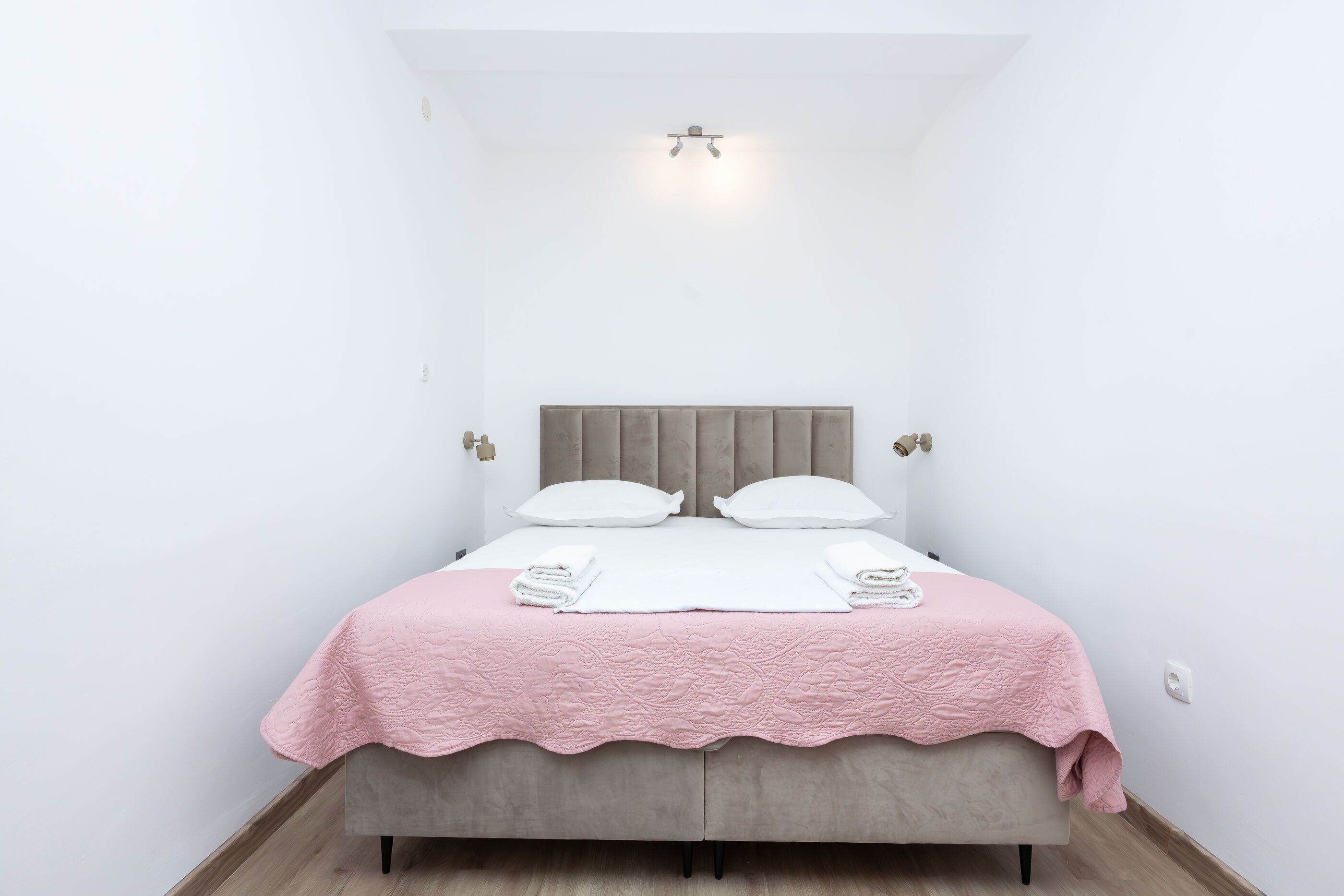 Ein Schlafzimmer mit Bett, Kissen, Kopfteil, Nachttisch und Beistelltisch.
