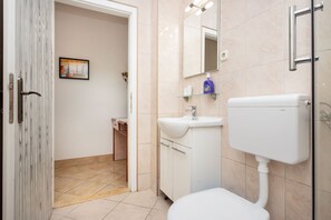 Un bagno con il water, un lavandino e uno specchio.