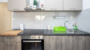A modern kitchen with a built-in oven, a stainless steel sink, and a wooden countertop. - Apartment Bogomir (Podgora)