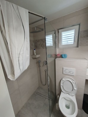 Ein modernes Badezimmer mit Duschabtrennung aus Glas, Toilette und Waschbecken mit Spiegel darüber.