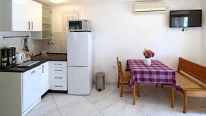 Eine kompakte Küche mit Kühlschrank, Mikrowelle und einem Essbereich mit Tisch und Stühlen.