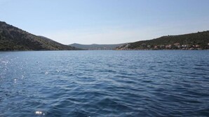 Ein ruhiger See, flankiert von Hügeln, unter einem klaren Himmel.