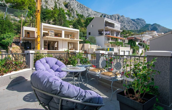 A balcony with a purple chair, a small round table, and potted plants. - Apartments Ozren (Omis)