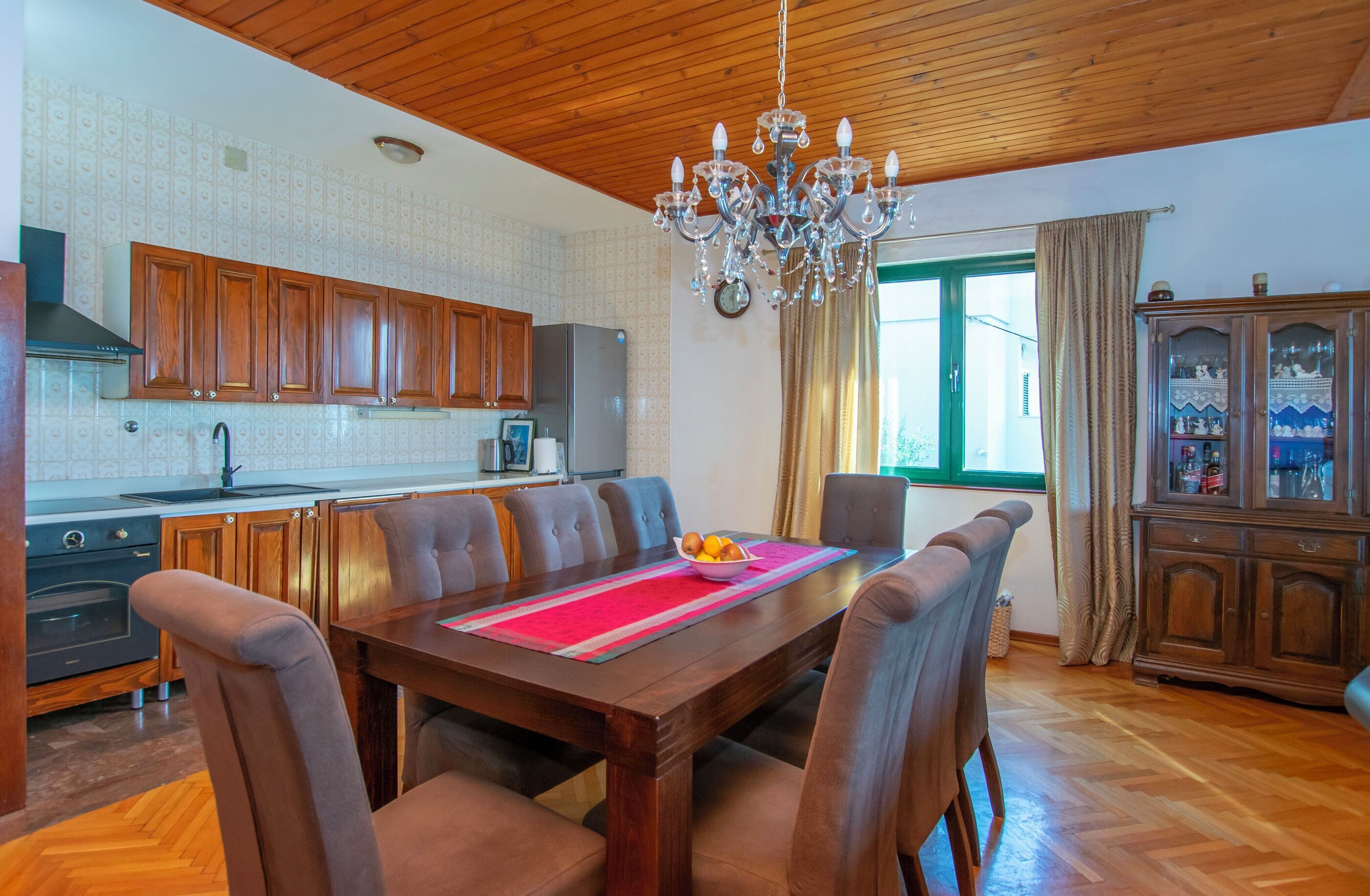 Uma sala de jantar com mesa de madeira, cadeiras e um lustre.