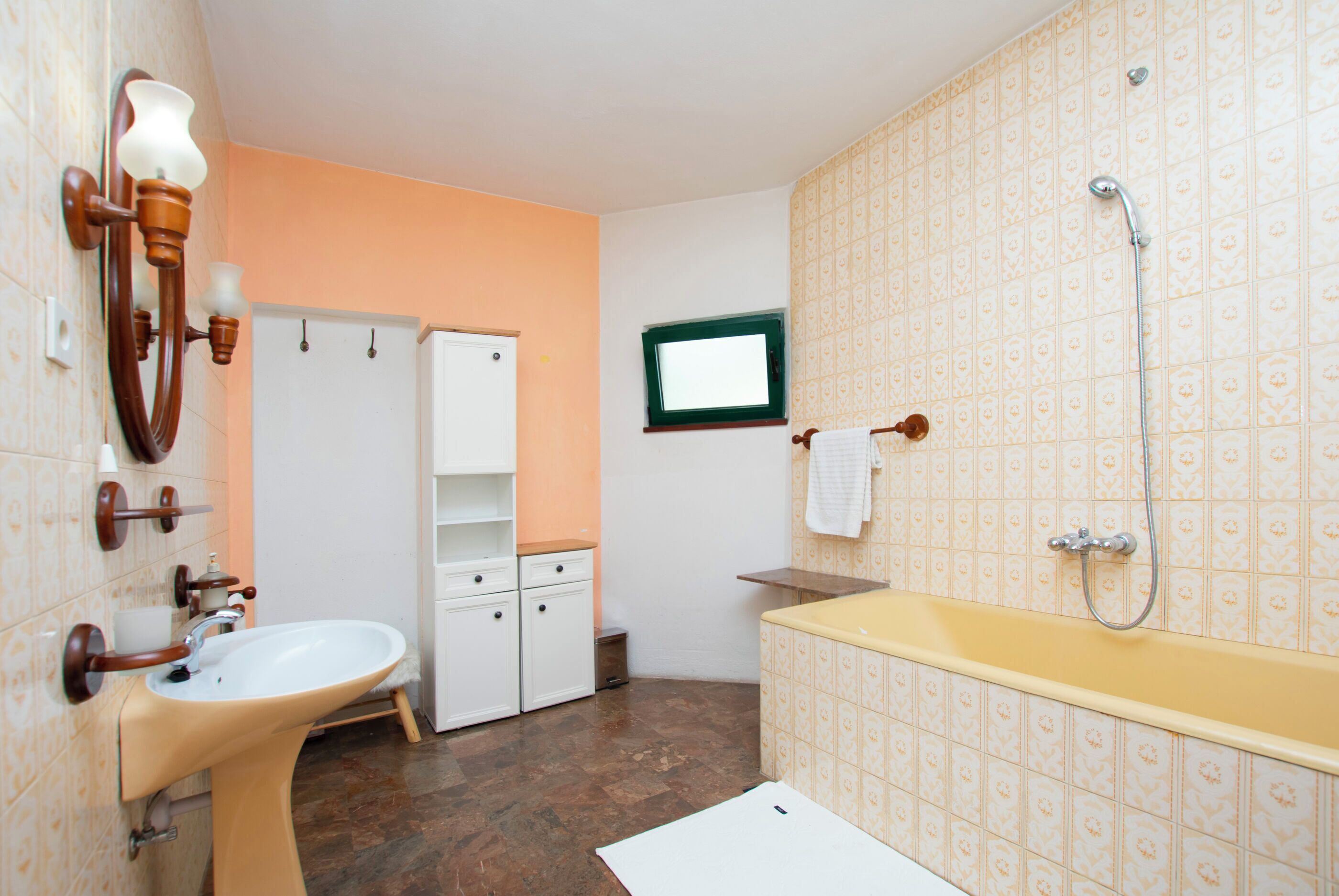 Ein Badezimmer mit Waschbecken, Spiegel, Dusche und einem kleinen Fenster.