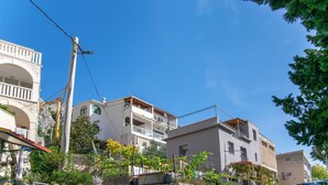 Una strada residenziale con edifici a più piani, un muro in pietra e un'auto parcheggiata.